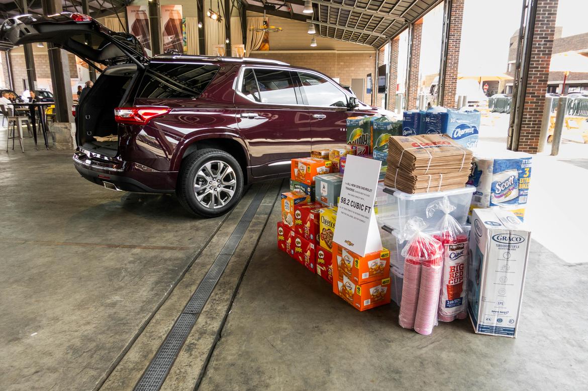 exterior view of a red 2018 chevrolet traverse next to a large pile of cargo being used to demonstrate cargo space